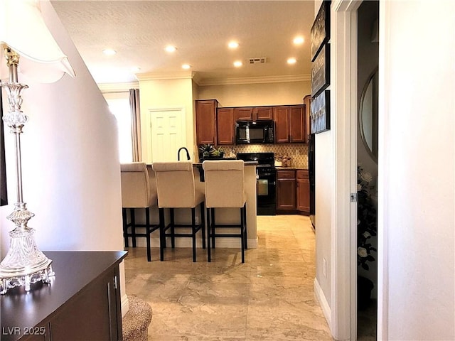 kitchen featuring tasteful backsplash, visible vents, black appliances, a textured ceiling, and a kitchen bar