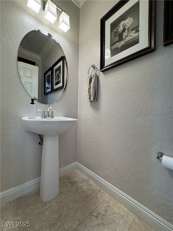 bathroom featuring a textured wall and baseboards