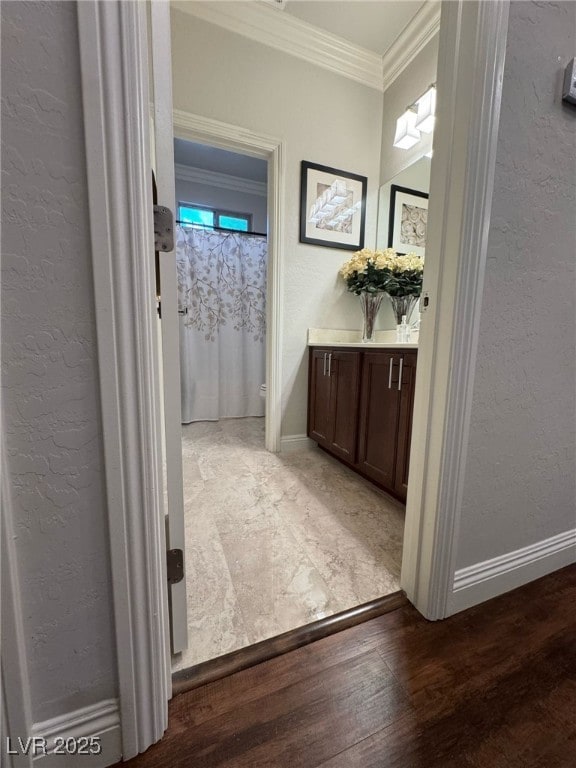 interior space with ornamental molding, a textured wall, and wood finished floors