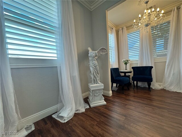 sitting room featuring dark wood-style floors, crown molding, baseboards, and an inviting chandelier