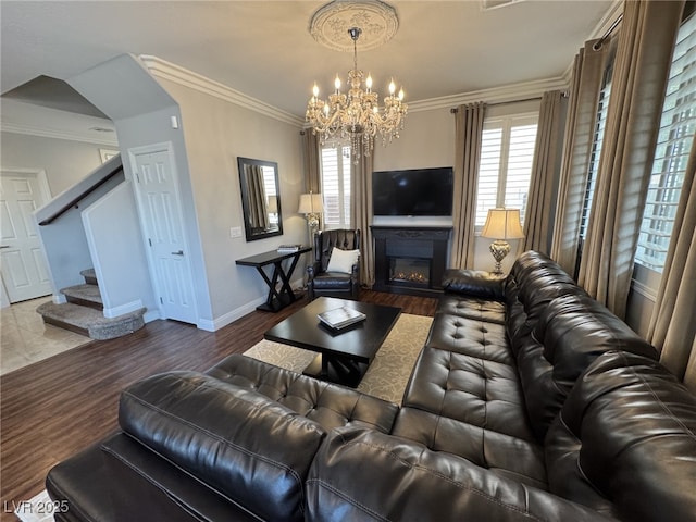 living area with stairs, wood finished floors, a glass covered fireplace, and crown molding