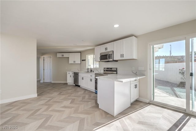 kitchen featuring sink, white cabinetry, stainless steel appliances, kitchen peninsula, and light parquet flooring