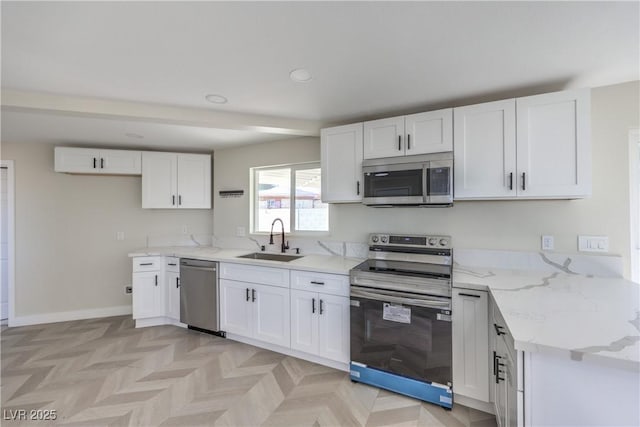 kitchen with light stone counters, stainless steel appliances, sink, and white cabinets