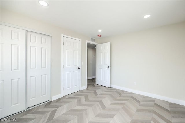 unfurnished bedroom featuring a closet and light parquet flooring