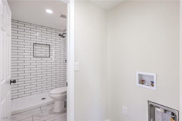 bathroom with tiled shower and toilet