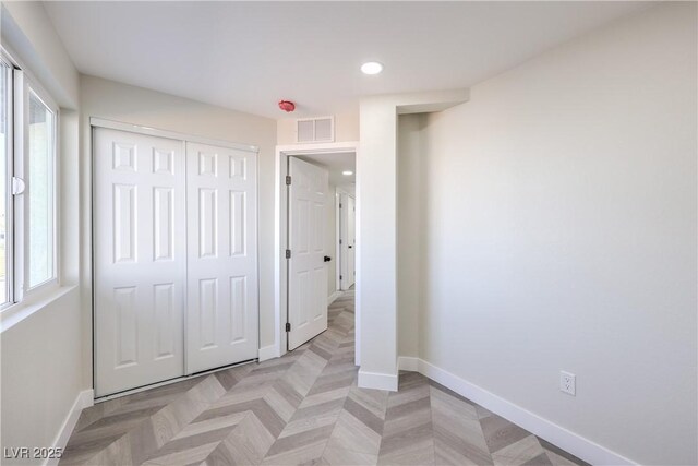 unfurnished bedroom with light parquet flooring and a closet