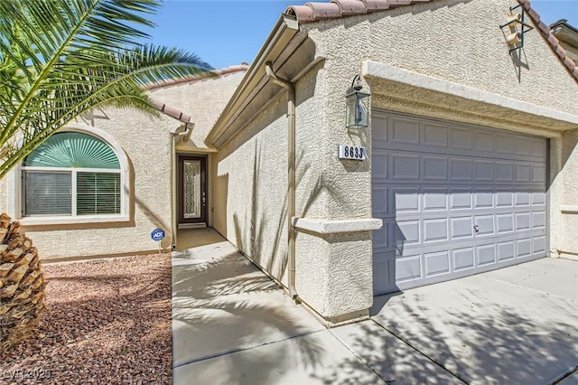 view of property exterior featuring a tile roof, driveway, an attached garage, and stucco siding