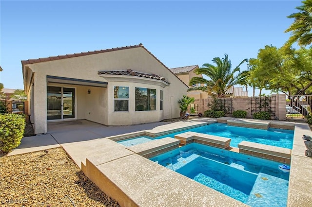 rear view of property featuring a tiled roof, fence, a patio area, a pool with connected hot tub, and stucco siding