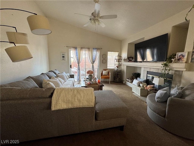 carpeted living room with a tiled fireplace, vaulted ceiling, and ceiling fan