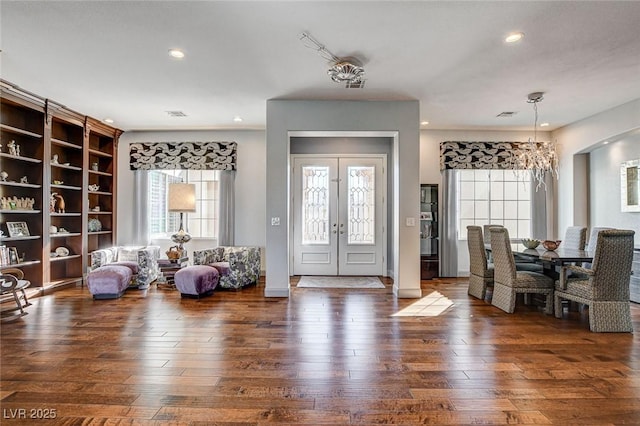 foyer with a healthy amount of sunlight, dark hardwood / wood-style floors, a chandelier, and french doors