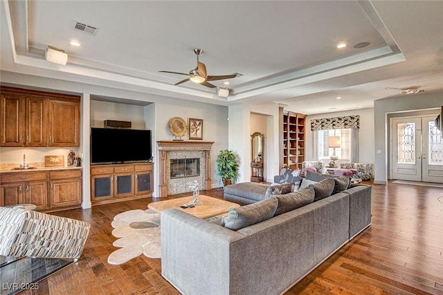 living room with dark hardwood / wood-style floors, a fireplace, and a tray ceiling