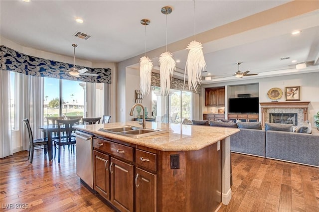 kitchen with dishwasher, an island with sink, hanging light fixtures, and sink