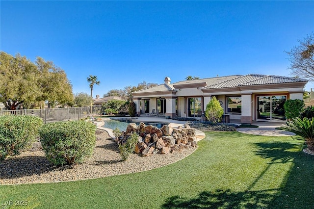 rear view of property featuring a yard, a fenced in pool, and a patio