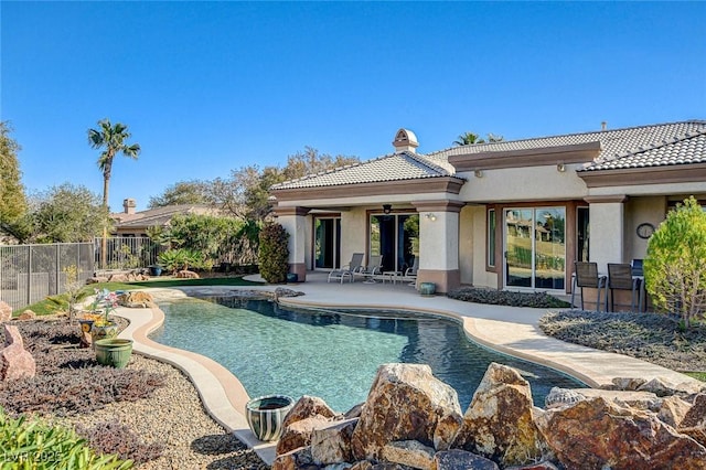 rear view of property featuring ceiling fan, a fenced in pool, and a patio