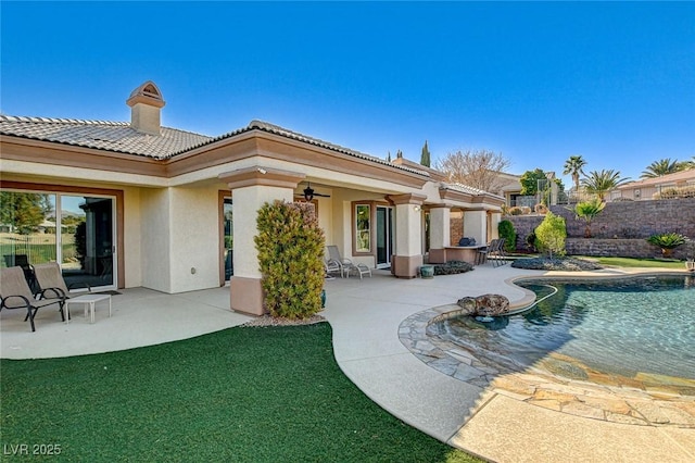 rear view of property with a fenced in pool, ceiling fan, and a patio area