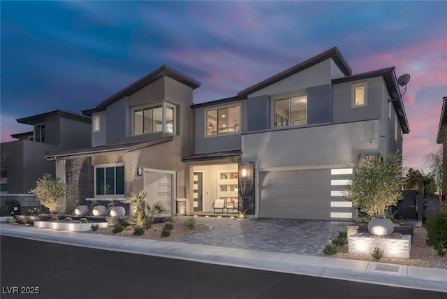 contemporary home featuring decorative driveway, an attached garage, and stucco siding