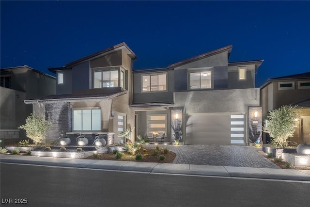 contemporary home featuring decorative driveway, an attached garage, and stucco siding