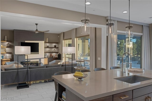 kitchen featuring recessed lighting, light countertops, a ceiling fan, open floor plan, and a sink