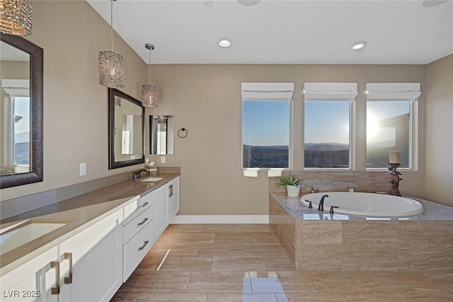 bathroom with a sink, double vanity, a garden tub, and a healthy amount of sunlight