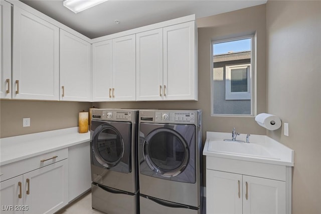 washroom with cabinet space, a sink, and washer and clothes dryer