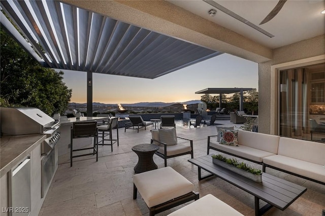 patio terrace at dusk featuring an outdoor kitchen, a grill, and outdoor lounge area