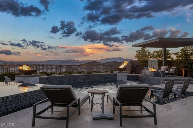 view of patio / terrace with an outdoor fire pit, a mountain view, and fence