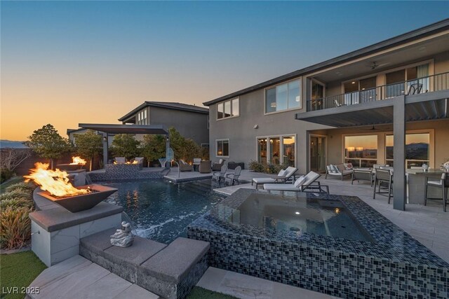 view of pool featuring an outdoor fire pit, a pool with connected hot tub, and a patio area