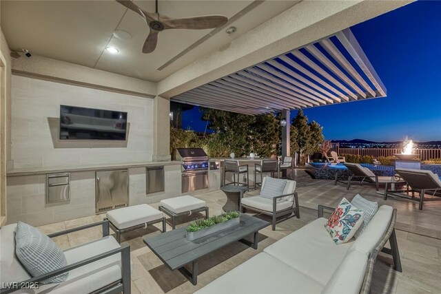 patio at twilight featuring an outdoor kitchen, an outdoor living space, a ceiling fan, and area for grilling