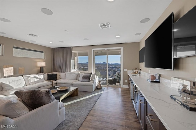 living area with dark wood-style floors, visible vents, and baseboards