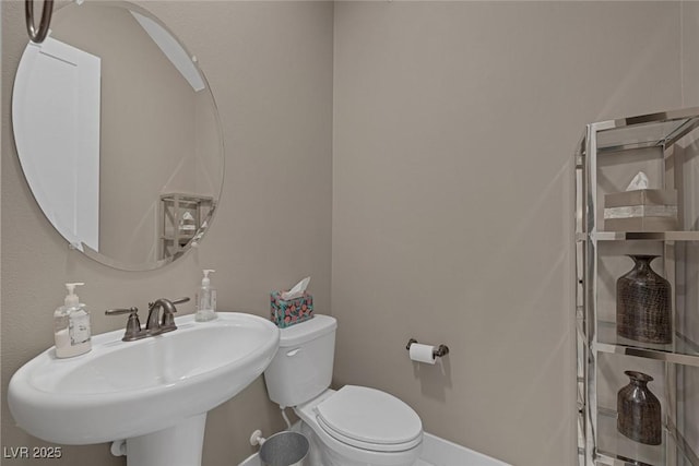 half bathroom featuring baseboards, a sink, and toilet