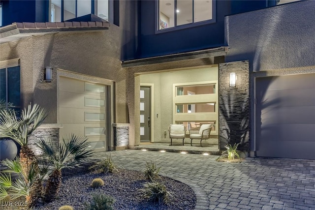 doorway to property with decorative driveway and stucco siding