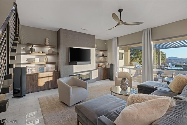 living area with visible vents, ceiling fan, stairway, marble finish floor, and a fireplace