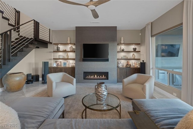 living room featuring ceiling fan, a fireplace, visible vents, built in features, and stairway