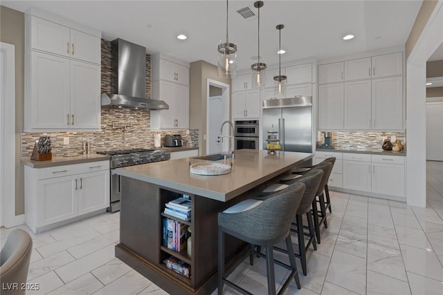 kitchen with stainless steel appliances, a sink, visible vents, marble finish floor, and wall chimney exhaust hood