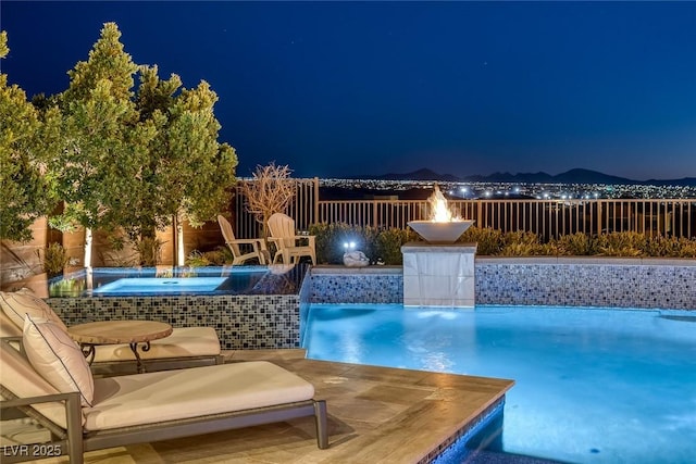 pool at night with a hot tub, fence, and a fenced in pool