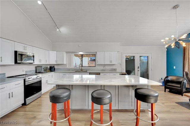 kitchen with a breakfast bar area, stainless steel appliances, a sink, white cabinets, and a center island