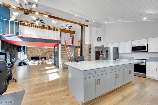 kitchen with stainless steel appliances, open floor plan, white cabinetry, a kitchen island, and high vaulted ceiling