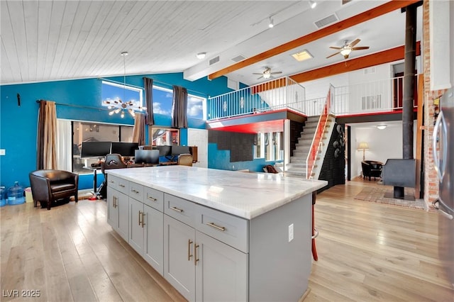 kitchen with a wood stove, light stone countertops, light wood-style flooring, and open floor plan