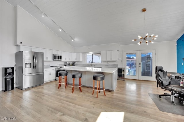 kitchen featuring white cabinets, a kitchen island, stainless steel appliances, light countertops, and pendant lighting