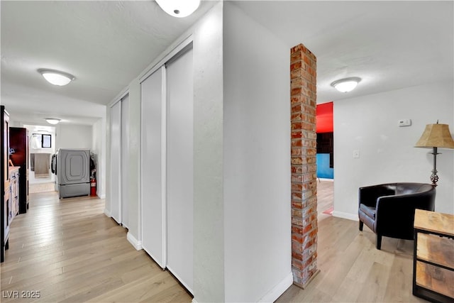 corridor with washer / dryer, light wood-style flooring, and baseboards