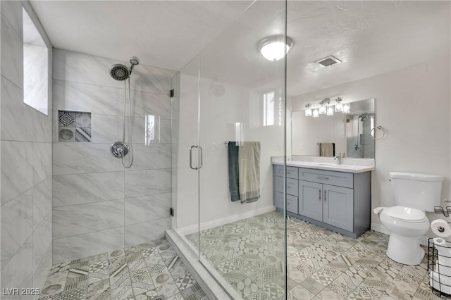 full bathroom featuring toilet, vanity, visible vents, baseboards, and a stall shower