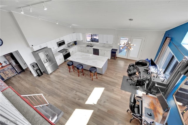 living area with light wood-type flooring, high vaulted ceiling, wine cooler, and a chandelier