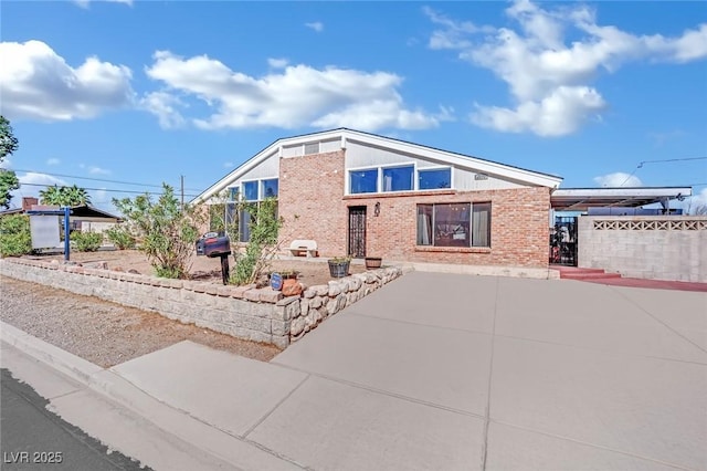 mid-century modern home featuring brick siding and fence