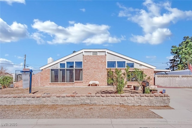 view of side of property featuring brick siding and fence