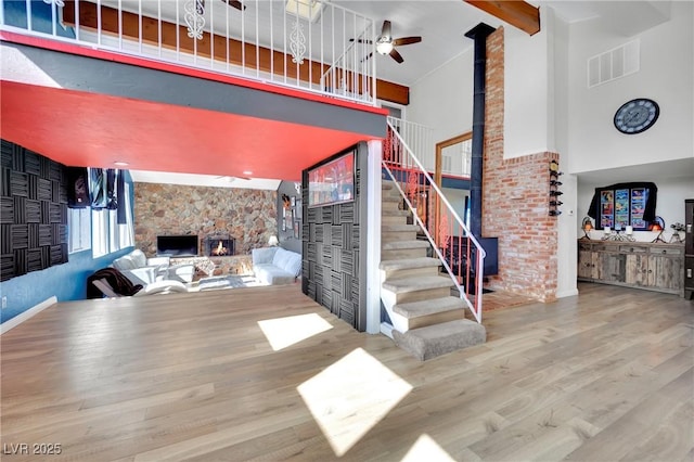 living room featuring high vaulted ceiling, wood finished floors, visible vents, stairway, and beamed ceiling