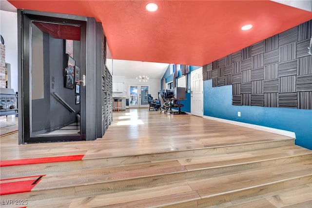 interior space with baseboards, lofted ceiling, wood finished floors, a chandelier, and recessed lighting