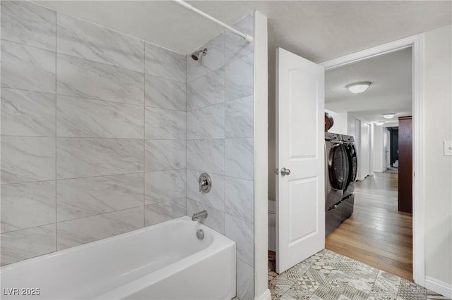 bathroom with shower / bathtub combination, washing machine and dryer, and baseboards