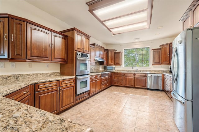 kitchen featuring light tile patterned flooring, tasteful backsplash, sink, light stone counters, and stainless steel appliances