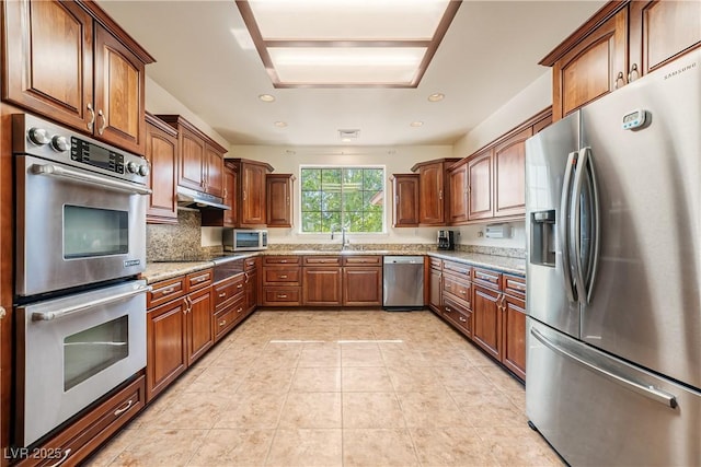 kitchen with sink, appliances with stainless steel finishes, light stone counters, light tile patterned flooring, and decorative backsplash