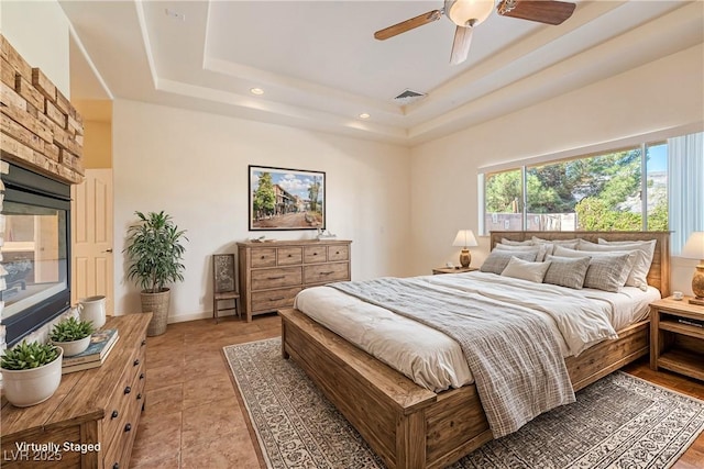 bedroom featuring light tile patterned flooring, ceiling fan, and a tray ceiling